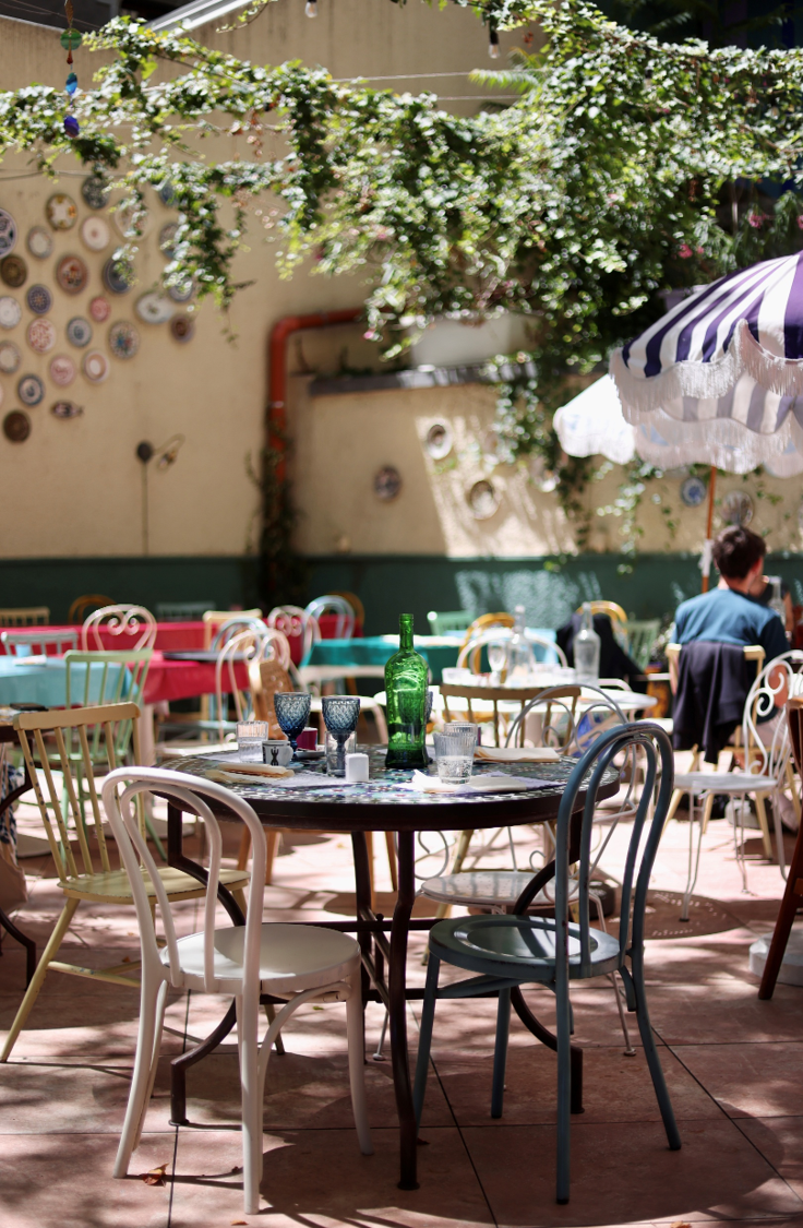 The colourful terrace at Un Po' Di Più with its tables, chairs and striped parasol