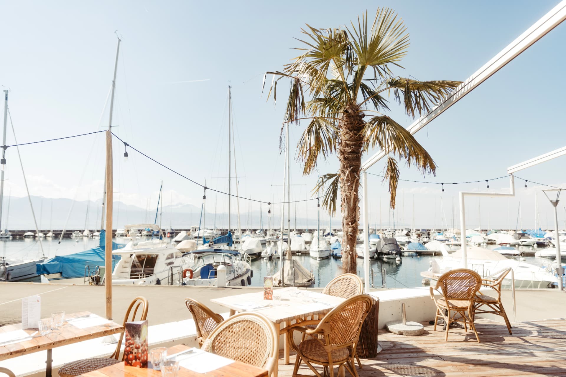 The wooden terrace of Villa Malfi with tables and views over the port of Lutry