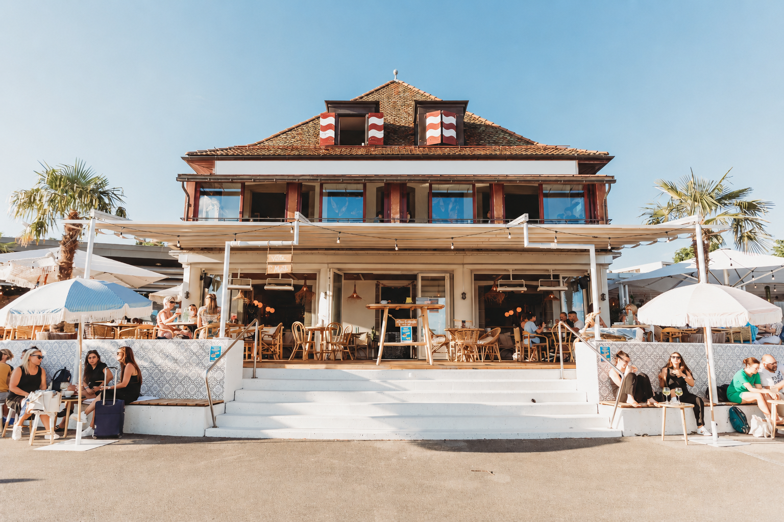 The façade of Villa Malfi in Lutry with its terrace, parasols and palm trees