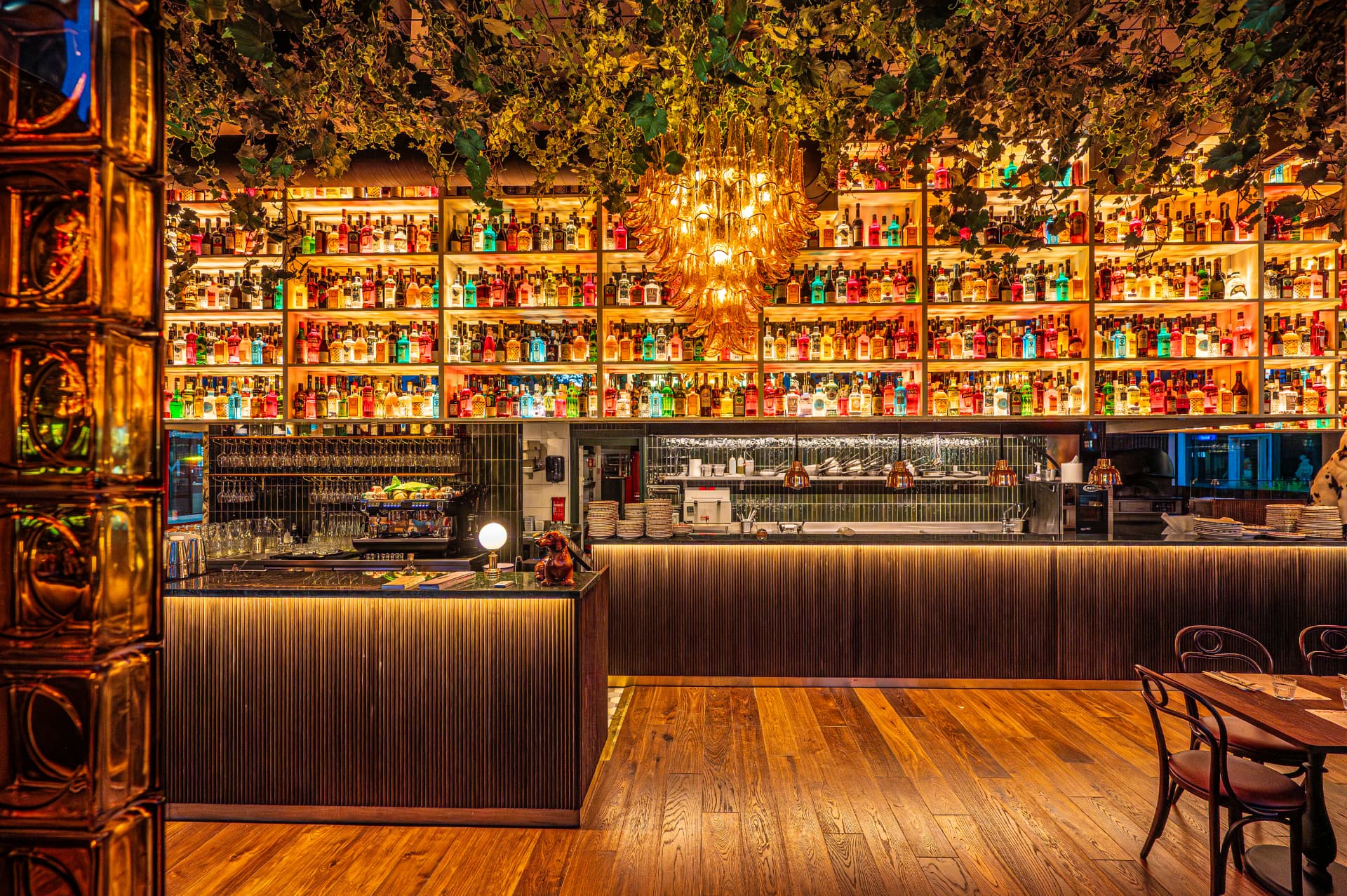 The bar at Gran Torino in the Flon district of Lausanne, with its illuminated bottle shelving, Murano chandeliers and hanging plants