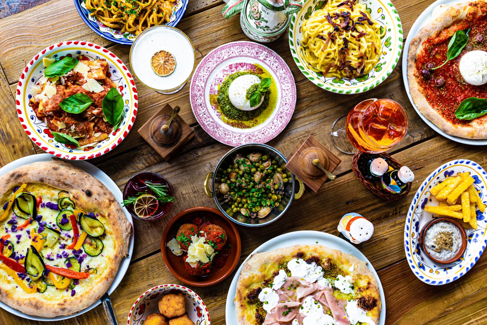 A generous Italian table at Un Po' Di Più with pizzas, pasta, burrata and colourful cocktails